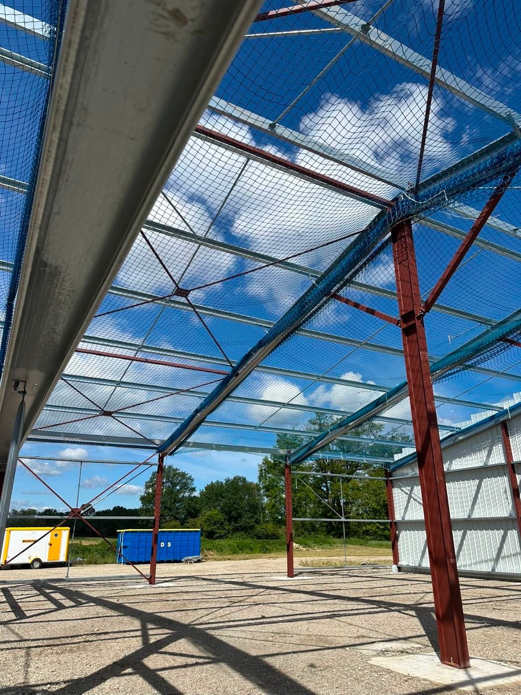 Filet anti-chute installé sous charpente, vue sur ciel bleu