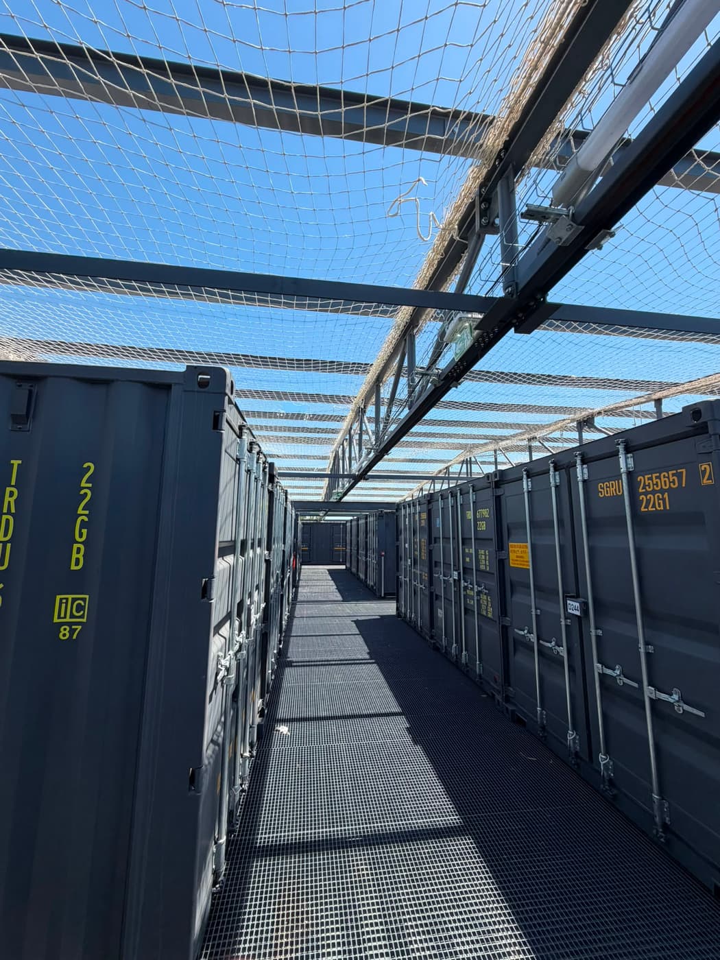 Filet anti-chute couvrant une allée entre des containers de stockage