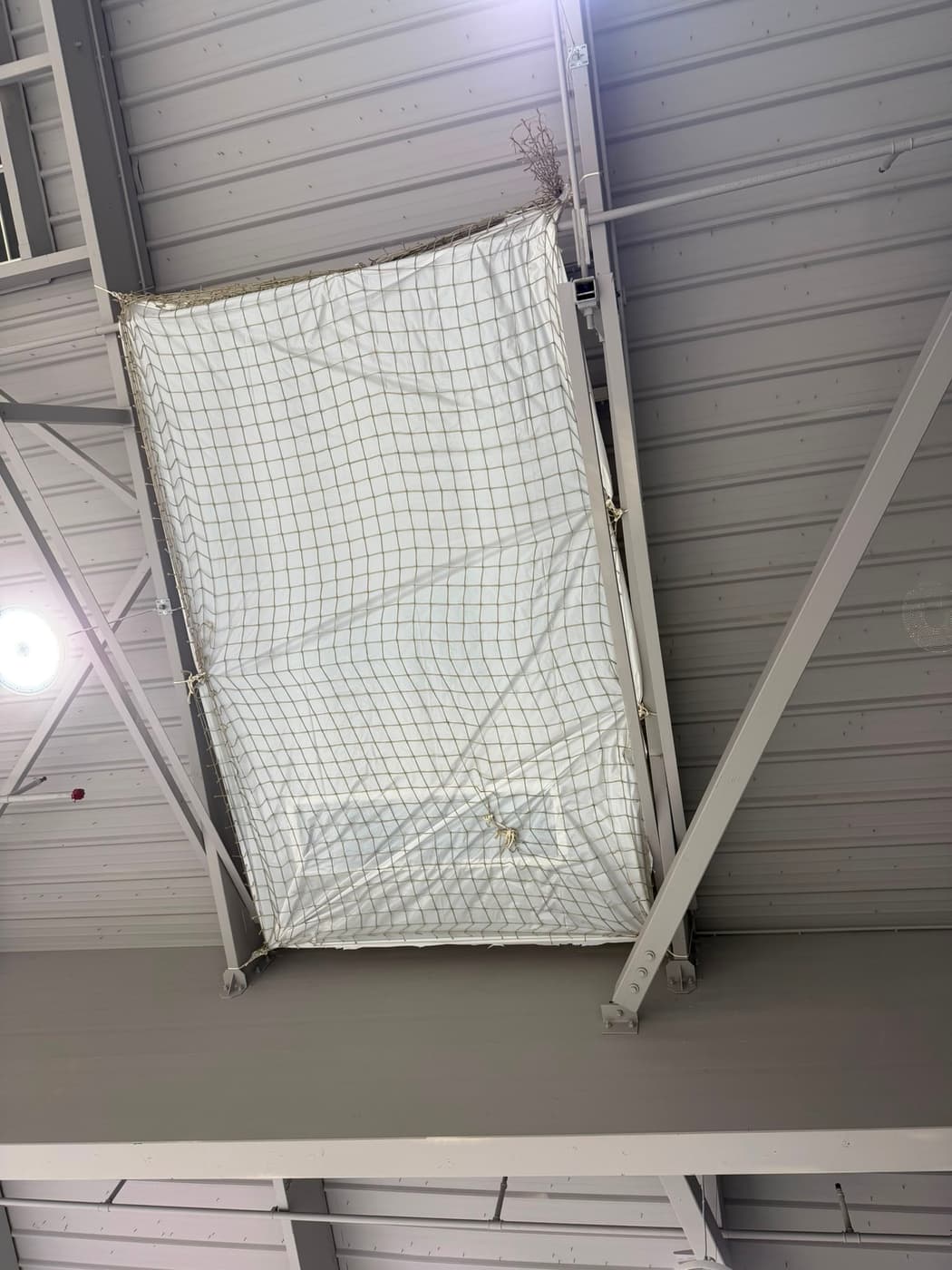Filet de récupération blanc tendu sous une toiture métallique